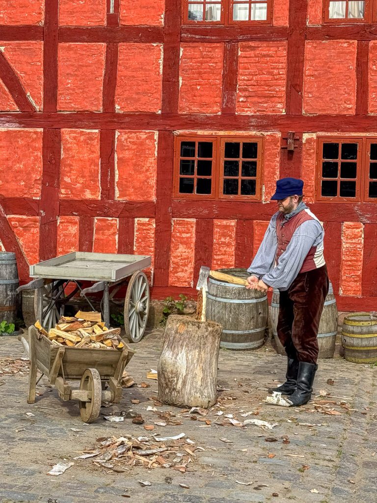 Statist hackt Holz in Den Gamle By Freiluftmuseum Aarhus, Dänemark