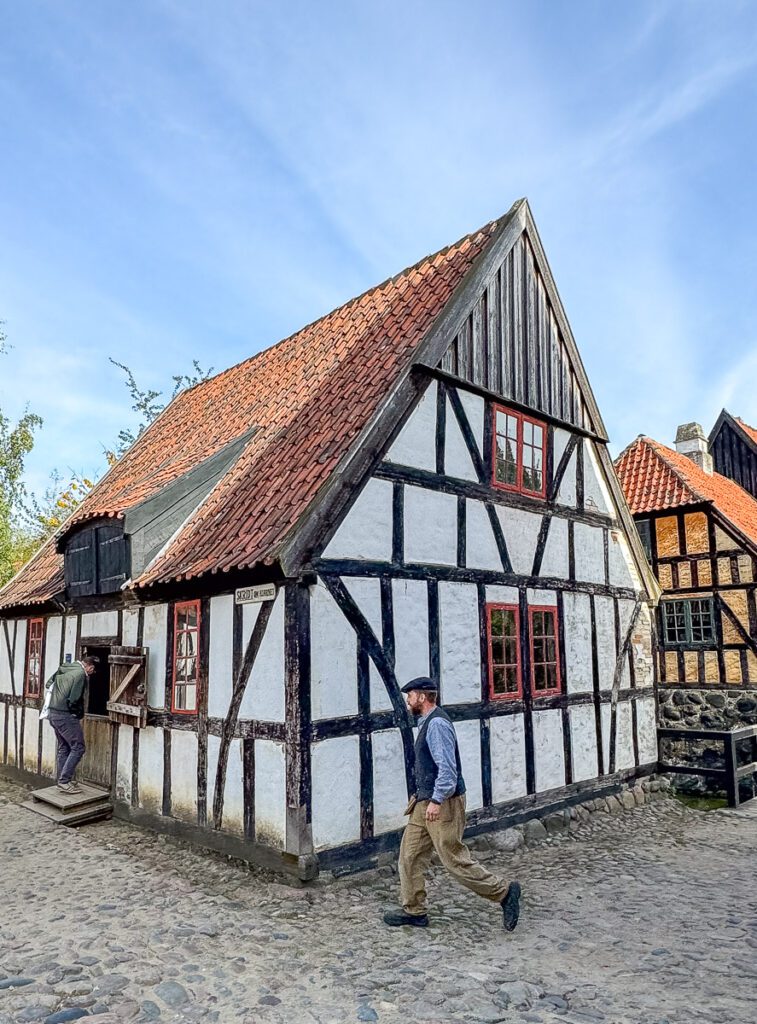 Mann geht vor Fachwerkhaus in Dänemark - Den Gamle By